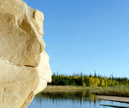 Clay erosion form of relief in the form of Golem heads - a human face on the mountain on the background of the tundra and the river of the Northern tundra of Yakutia.の写真素材