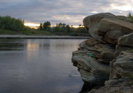 A stone ledge in a beautiful picturesque place of the North of Yakutia is spoiled by the garbage of broken bottles of tourists at sunset in the evening.の写真素材