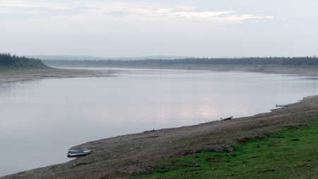 Parking of boats and boats in the wild North of Yakutia on the turn of the Vilyui river in the evening to the banks of the taiga.の写真素材