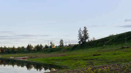 Boats and boats are parked on the banks of the river vilyu near the cliffs with the village of ulus Suntar in the North of Yakutia in the spruce forest.の写真素材