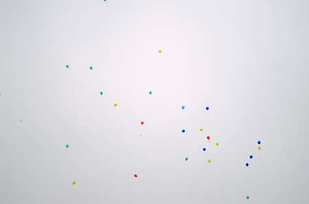 Bright colored gel balloons blue, red and yellow fly up in the sky on the background of the sun on holiday.の写真素材