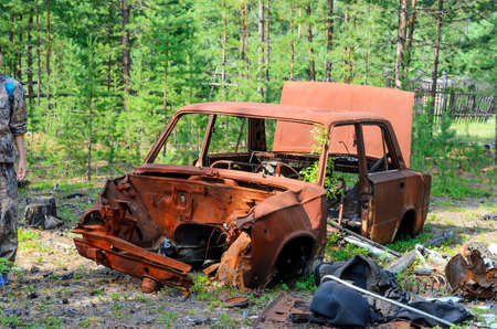 Iron rusty body of the Soviet car lies in a young spruce forest in the tundra of Yakutia.の写真素材