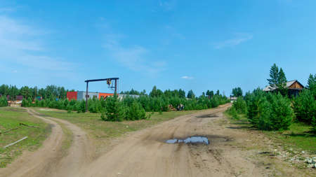Fork of the road to residential village houses and working area in the Northern village of Yakutia on the background of spruce forest tundra.の写真素材