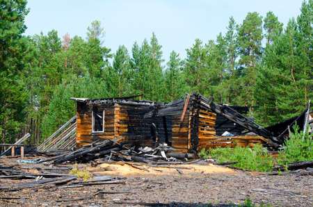 The remains of a burned wooden new house after a fire without a roof with charred logs in the forest of the Northern taiga of Yakutia.の写真素材