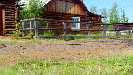 The grass grows near the road in the village at a private house from a bar and a shed with a transparent fence in Yakutia.の写真素材