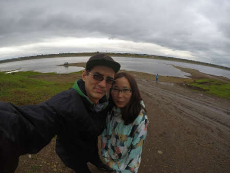 Russian man with glasses takes a selfie with an Asian girl standing on the Bank of the North river in cloudy weather.の写真素材