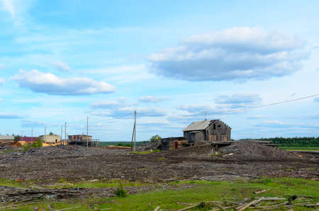 An old abandoned sawmill stands on the Bank of the Northern river and the forest with littered boards and old buildings in Yakutia.の写真素材