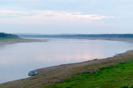 Boats and ships are on the stone Bank of the wild turn of the Northern river vilyu foggy evening in the deserted taiga of Yakutia in the autumn.の写真素材