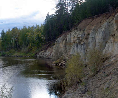 The cliff in the woods North of the river in Yakutia, Kempendyay with spruce forest and clay erosion forms in the autumn in the forest.の写真素材