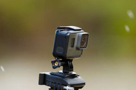 Action camera is recording video on a blurred background of snow and grass with a river.の写真素材