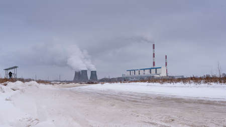 A photographer in the distance takes pictures of the heat power station near the road with smoke from the pipes.の写真素材