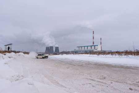 Russia, Novosibirsk - November 30, 2019. An unknown person takes a video on a tripod on a hill on a fast-moving sideways Russian white old car "VAZ Zhiguli".のeditorial素材