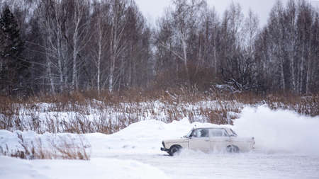 Russia, Novosibirsk - November 30, 2019. Russian low old car "VAZ-Zhiguli" goes drifting in the winter turning the wheels raising snow with a camera "Gopro" on the roof on the turn.のeditorial素材