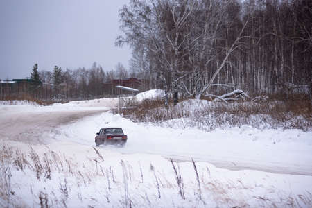 Russia, Novosibirsk - November 30, 2019. Russian dark old low car "VAZ Zhiguli" is driving fast on a winter snow road in the field.のeditorial素材