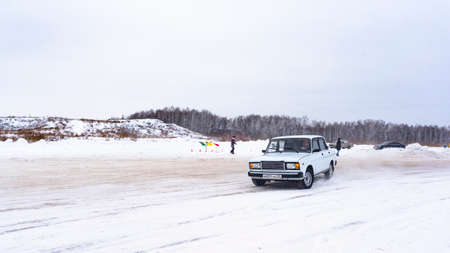Russia, Novosibirsk - November 30, 2019. Russian light old low car "VAZ Zhiguli" quickly goes sideways through the snow in the drift on the road turning the wheel.のeditorial素材