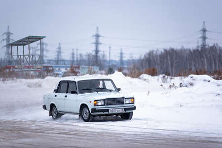 Russia, Novosibirsk - November 30, 2019. Russian old modified white car "VAZ-Zhiguli" goes fast drift turning the wheels raising snow in winter.のeditorial素材