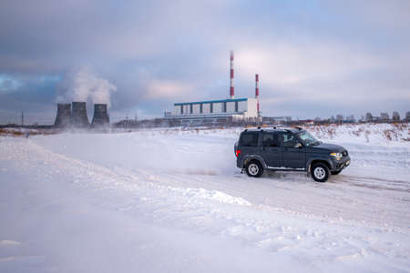 Russia, Novosibirsk-January 20, 2020 Russian SUV "UAZ Patriot" quickly goes on a snowy road in the field in winter against the background of a heat power station.のeditorial素材