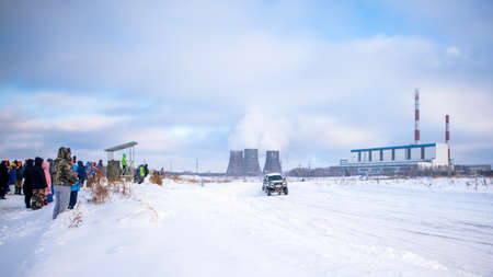 Russia, Novosibirsk-January 20, 2020 Russian SUV "UAZ Patriot" quickly goes on a snowy road in the field in winter against the background of the heat power station and the audience looking at it.のeditorial素材