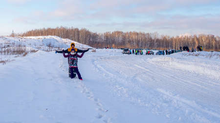 Russia, Novosibirsk-January 20, 2020 An unknown girl with a man standing on a snowdrift having fun in the winter, showing figures with her hands.のeditorial素材