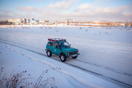 Russia, Novosibirsk-January 20, 2020 Russian SUV "Lada Niva" is driving fast on a snowy road in a field in winter against the background of the city's houses.のeditorial素材