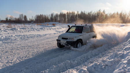 Russia, Novosibirsk-January 20, 2020 All-wheel drive 4x4 white SUV "Suzuki Escudo" with fast rides raising an avalanche bumper on the road in winter in the sun.のeditorial素材