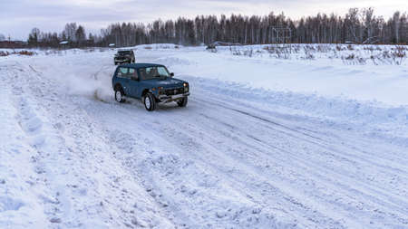 Russia, Novosibirsk-January 20, 2020 Two Russian SUV "Lada Niva" quickly go on a snowy road in the field in the winter, clinging to the snowstorm wheel.のeditorial素材