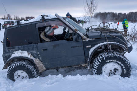 Russia, Novosibirsk-January 20, 2020 4x4 all-Wheel drive SUV "Suzuki Escudo" with the driver in the open window and a cable winch on the hood goes through a snowdrift in winter.のeditorial素材