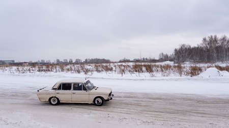 Russia, Novosibirsk - November 30, 2019. Russian old low car "VAZ Zhiguli" goes fast on a winter road with a passenger and a camera "Go Pro" on the roof.のeditorial素材