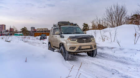 Russia, Novosibirsk-March 5, 2020. Russian white SUV UAZ Patriot rides on a snowy road in winter.