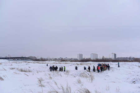 Russia, Novosibirsk-March 23, 2020. A lot of people take turns walking in the snow on an off-road highway in winter with cameras and selfie sticks.のeditorial素材