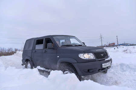 Russia, Novosibirsk-March 5, 2020. Russian black 4x4 SUV in protective paint "UAZ Patriot Pickup" is driving fast on the road in the snow in winter.のeditorial素材