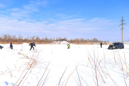 Russia, Novosibirsk-March 23, 2020. Russian offroad SUV "UAZ Patriot 4x4" in the winter in the snow stands next to people playing war games.のeditorial素材