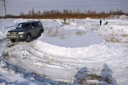 Russia, Novosibirsk-March 23, 2020. Offroad SUV "Nissan Patrol 4x4" drives fast on the road before turning into a field in the snow in winter with shadows of people.のeditorial素材