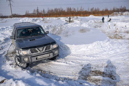 Russia, Novosibirsk-March 23, 2020. Offroad SUV "Nissan Patrol 4x4" quickly rides in the snow field in winter with a smiling cheerful passenger.のeditorial素材