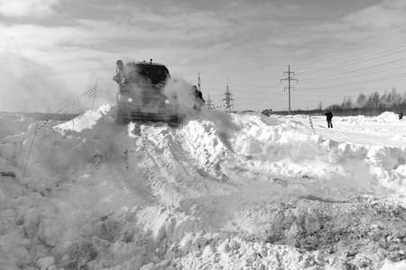 Russia, Novosibirsk - March 13, 2020. Black and white photo of an Offroad SUV "Range Rover 4x4" driving on a snowy mountain in colored blue smoke with a man outside.のeditorial素材