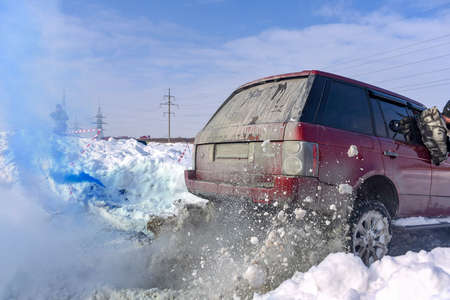 Russia, Novosibirsk - March 13, 2020. Off-road SUV "Range Rover 4x4" leaves on a snowy road in winter with a man leaning out of the window, raising a Blizzard.のeditorial素材