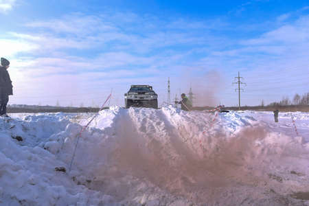 Russia, Novosibirsk-March 13, 2020. Offroad SUV "Suzuki Escudo" 4x4 rides on a snowy mountain in the clouds of colored brown smoke in winter on a broken road during the day.のeditorial素材
