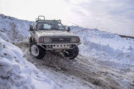 Russia, Novosibirsk-March 23, 2020. The old ffroad car "Subaru 4x4" converted from a sedan quickly with a spray of snowstorms goes on a snowy road in winter on the turn turning the wheels.のeditorial素材
