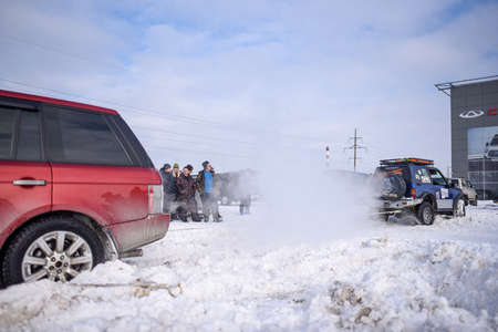 Russia, Novosibirsk - March 13, 2020. Offroad SUV "Range Rover 4x4" pulls the rope with a jeep "Suzuki Escudo" in winter in the snow in the Parking lot.のeditorial素材