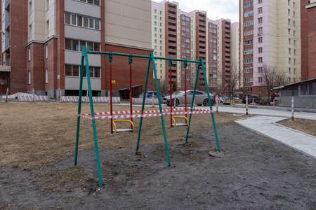 Novosibirsk, Russia-April 12, 2020. Swings on the Playground in the courtyard of an apartment building are taped closed to the public due to the quarantine of the covid 19 coronavirus epidemic.のeditorial素材