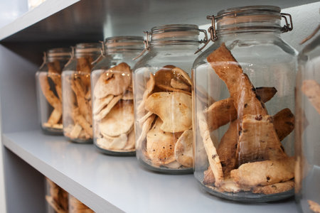 Row of glass jars filled with assorted baked crackers on a shelf, showcasing rustic snacks in clear storage with shallow depth of field.の写真素材