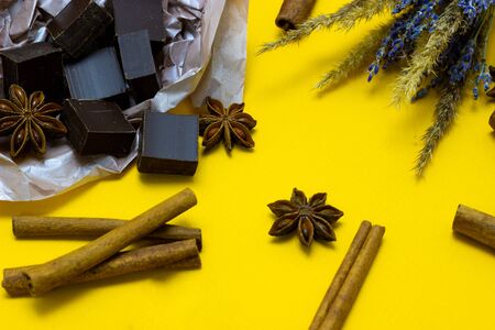 chocolate with lavender flowers, cinnamon and star anise over yellow backgroundの写真素材