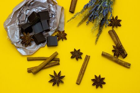 chocolate with lavender flowers, cinnamon and star anise over yellow backgroundの写真素材