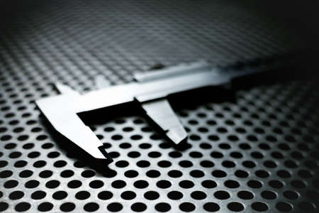 Vernier caliper on metal perforated surface with highlightsの写真素材