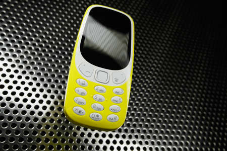 Shockproof yellow phone on metal surface. Selective focus