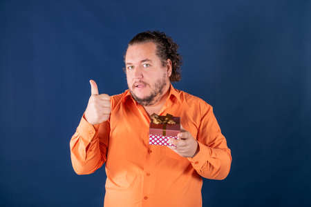 Funny fat man opens a box with a gift. Birthday celebrationの写真素材