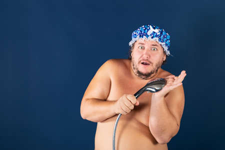 Funny fat man in blue cap sing in the shower. Fun and cleanlinessの写真素材