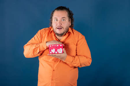 Funny fat man opens a box with a gift. Birthday celebrationの写真素材