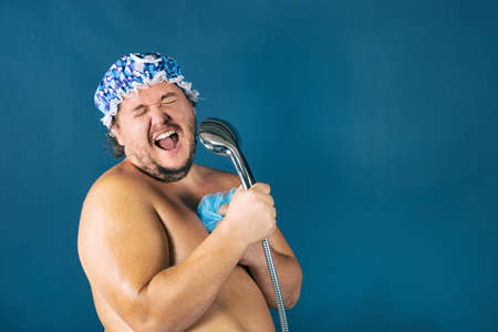 Funny fat man in blue cap sing in the shower. Fun and cleanlinessの写真素材