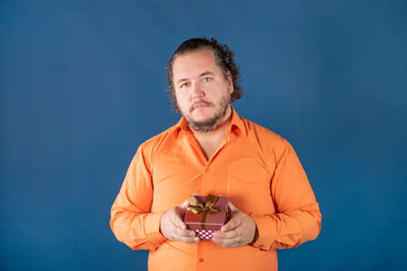 Funny fat man opens a box with a gift. Birthday celebrationの写真素材